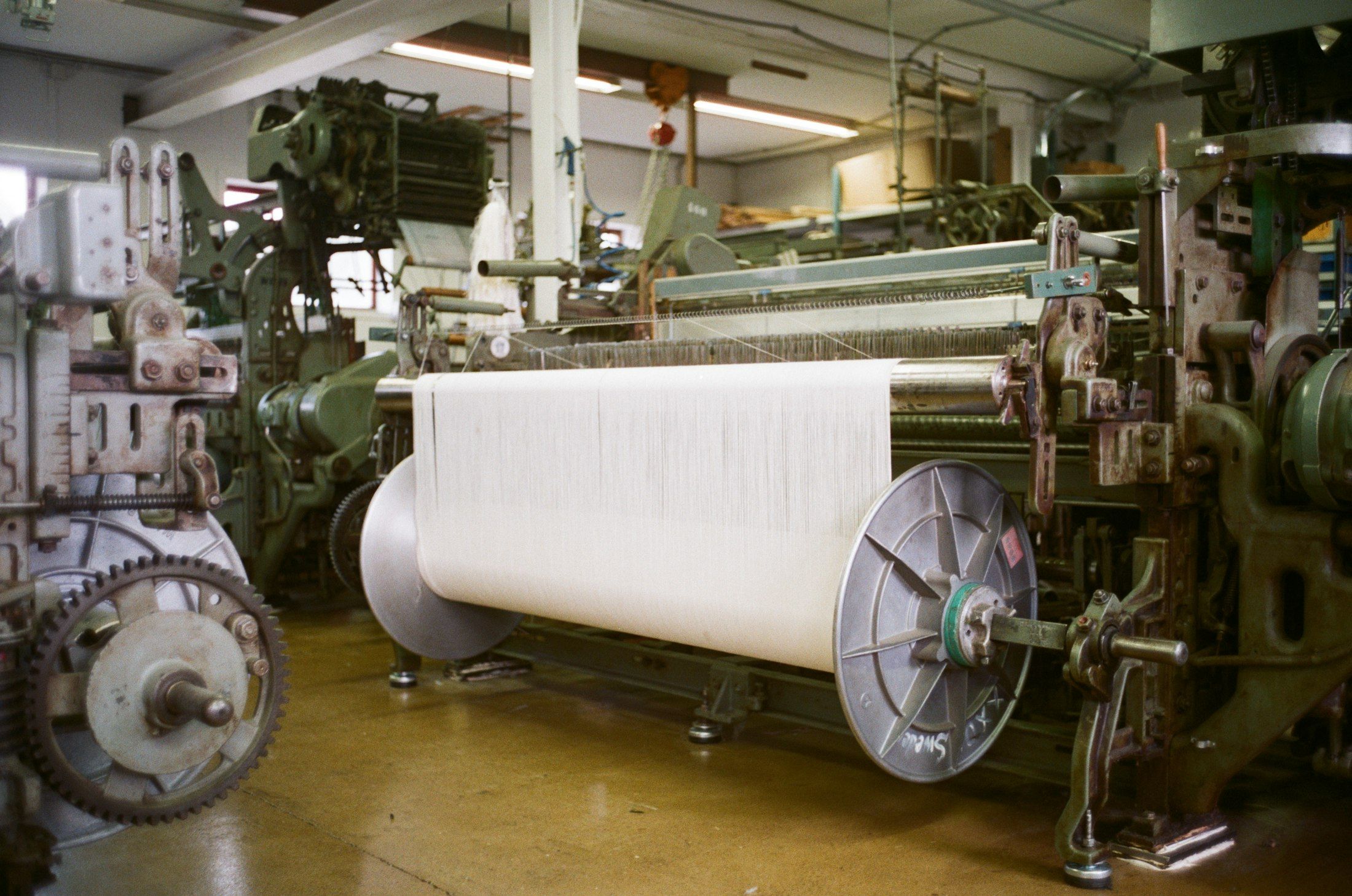 Industrial looms with a large roll of white fabric