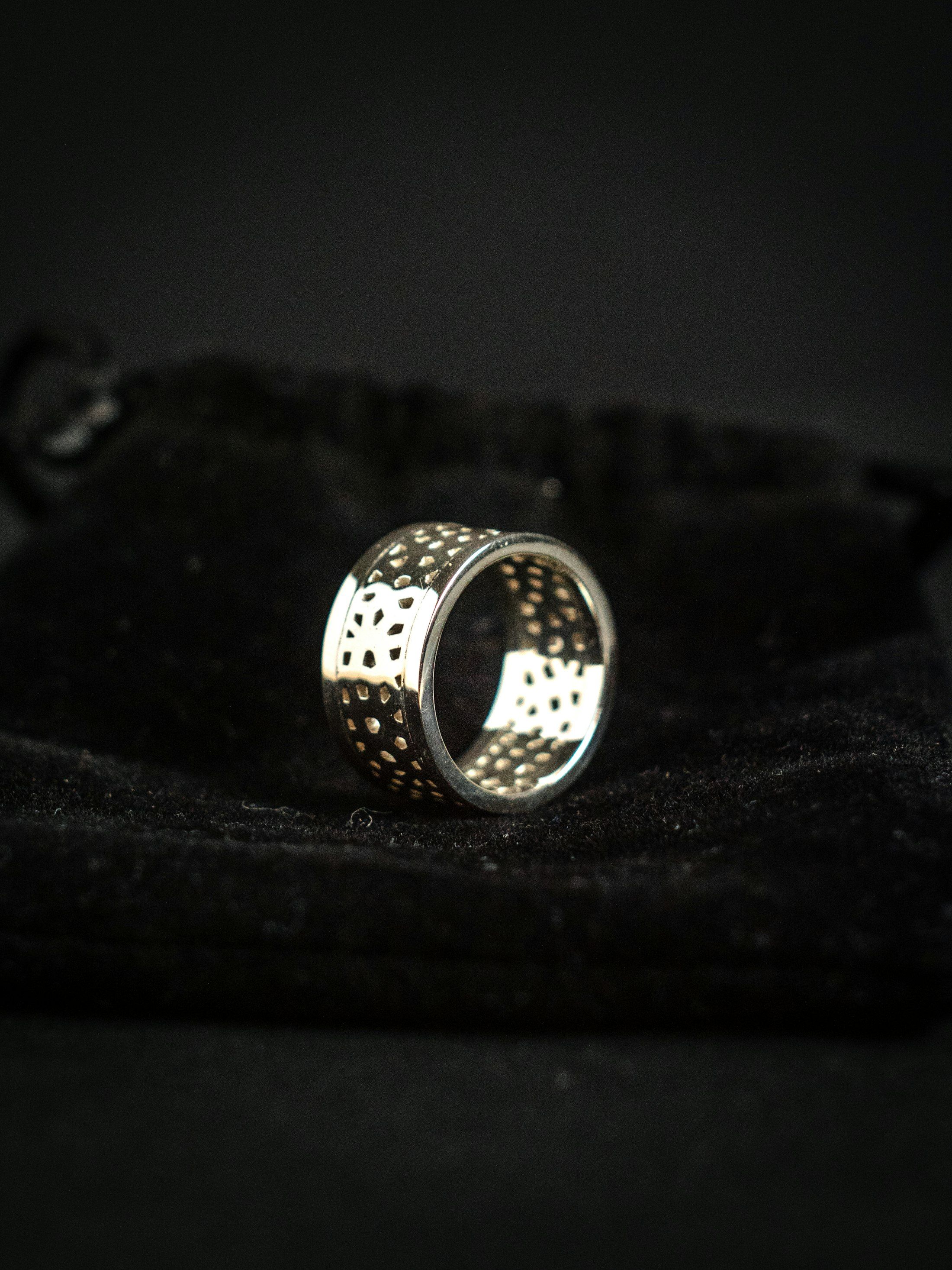 A perforated sterling silver band ring on black fabric