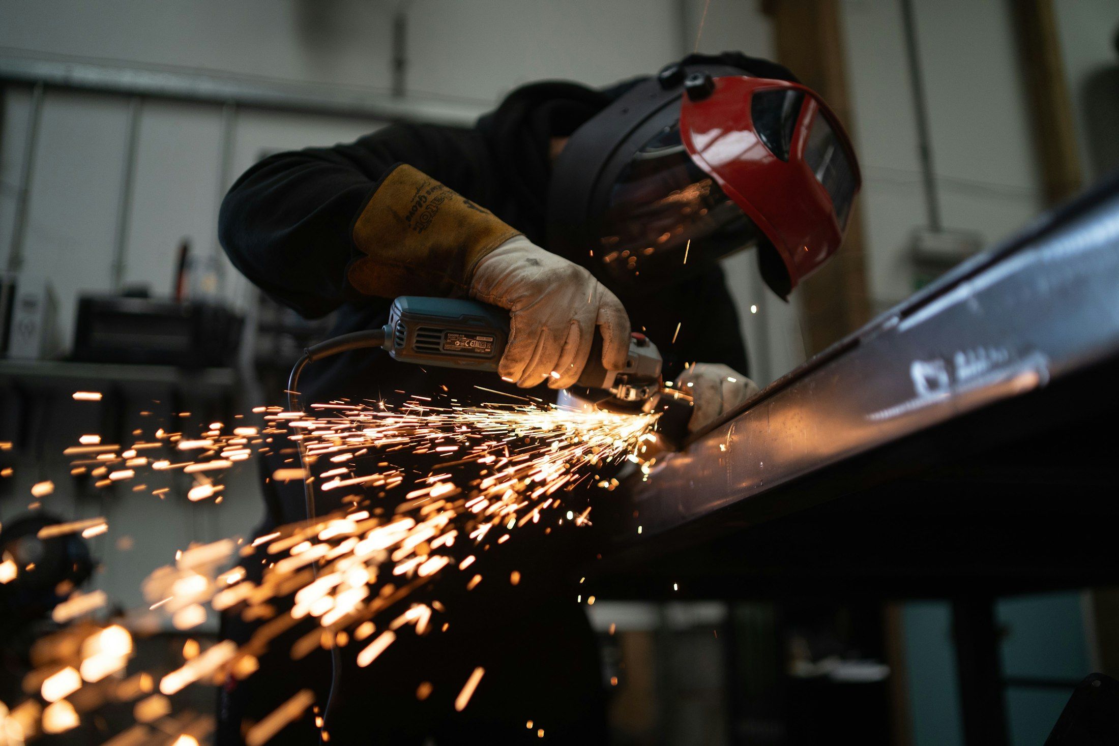 A worker grinding a steel beam, sparks flying in a dark workshop